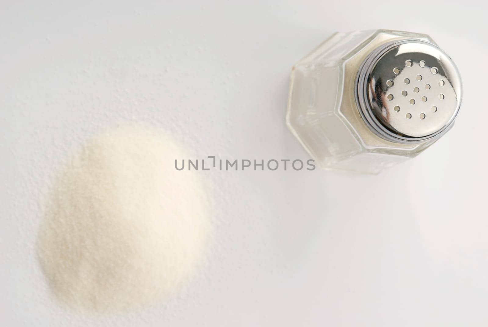 High angle view of a salt shaker with a heap of salt