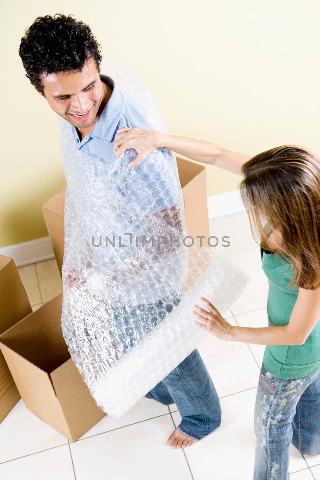 High angle view of a mid adult woman wrapping a bubble wrap around a young man