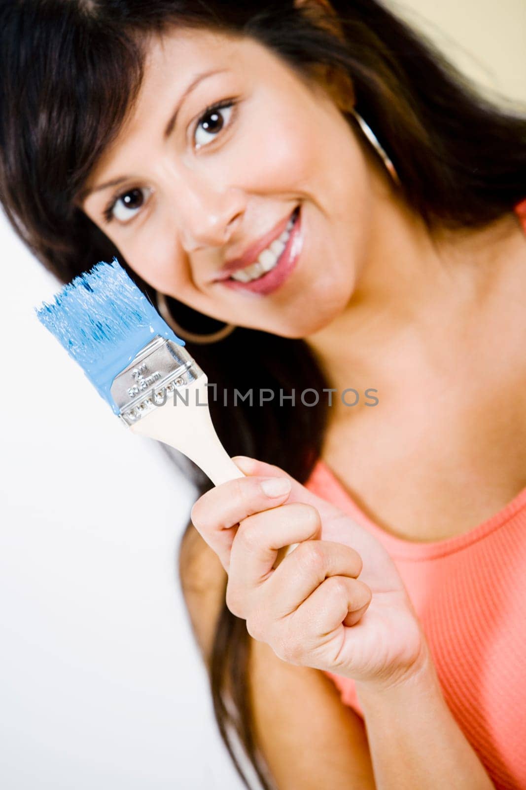 Portrait of a young woman holding a paintbrush and smiling