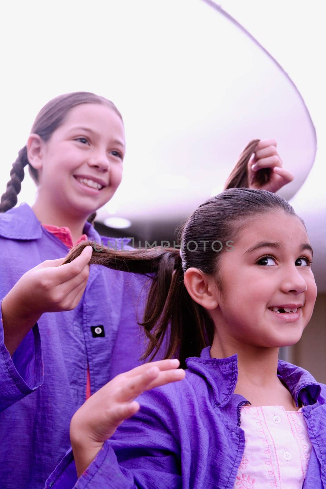 Close-up of a girl making braids of another girl