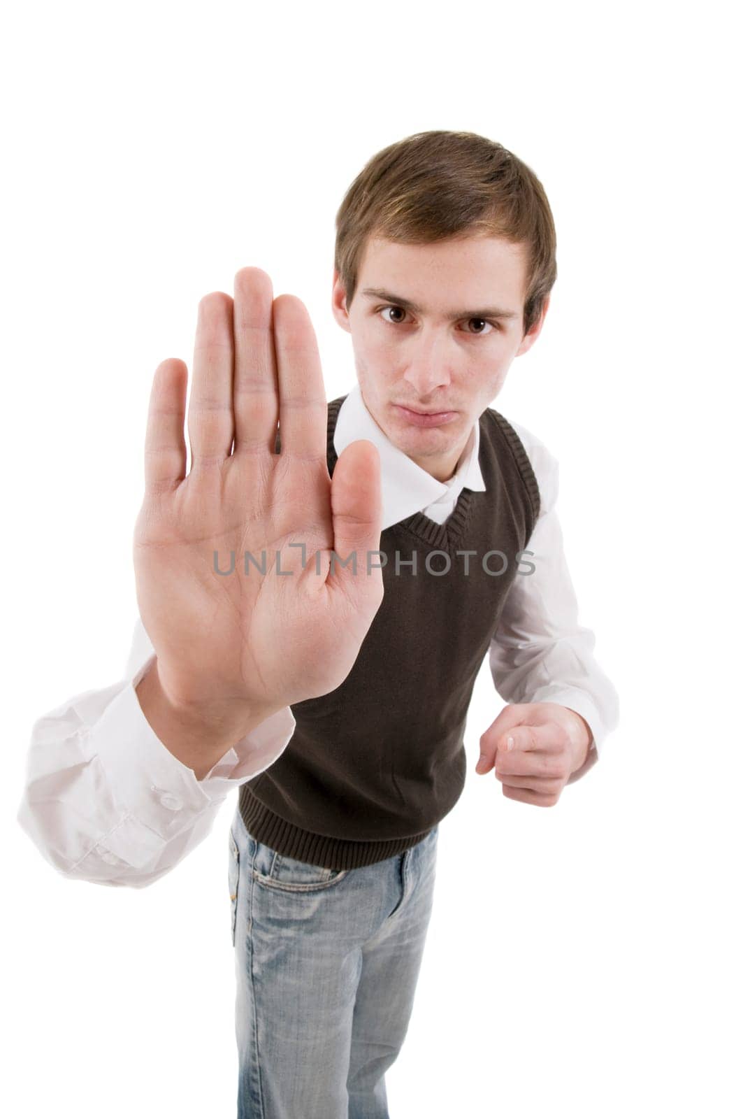 Frontal torso shot of a young man with his right palm stretched towards the camera and looking aggressively at the camera against white background.