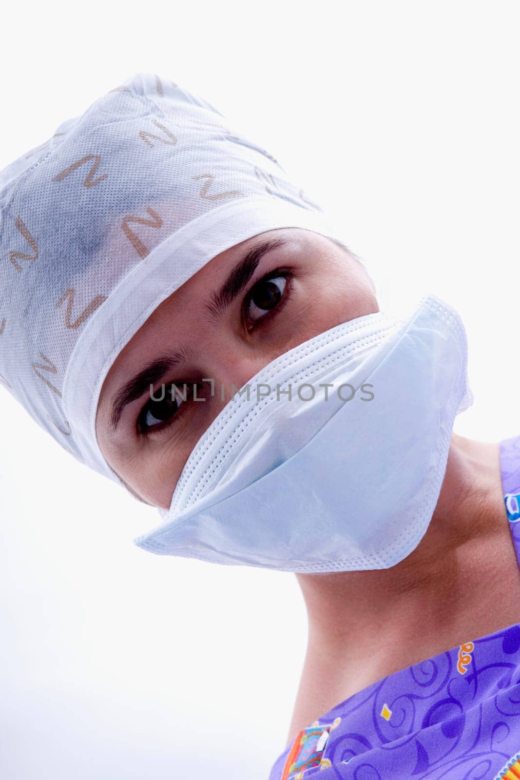 Close-up of a female nurse in a surgical mask and a surgical cap