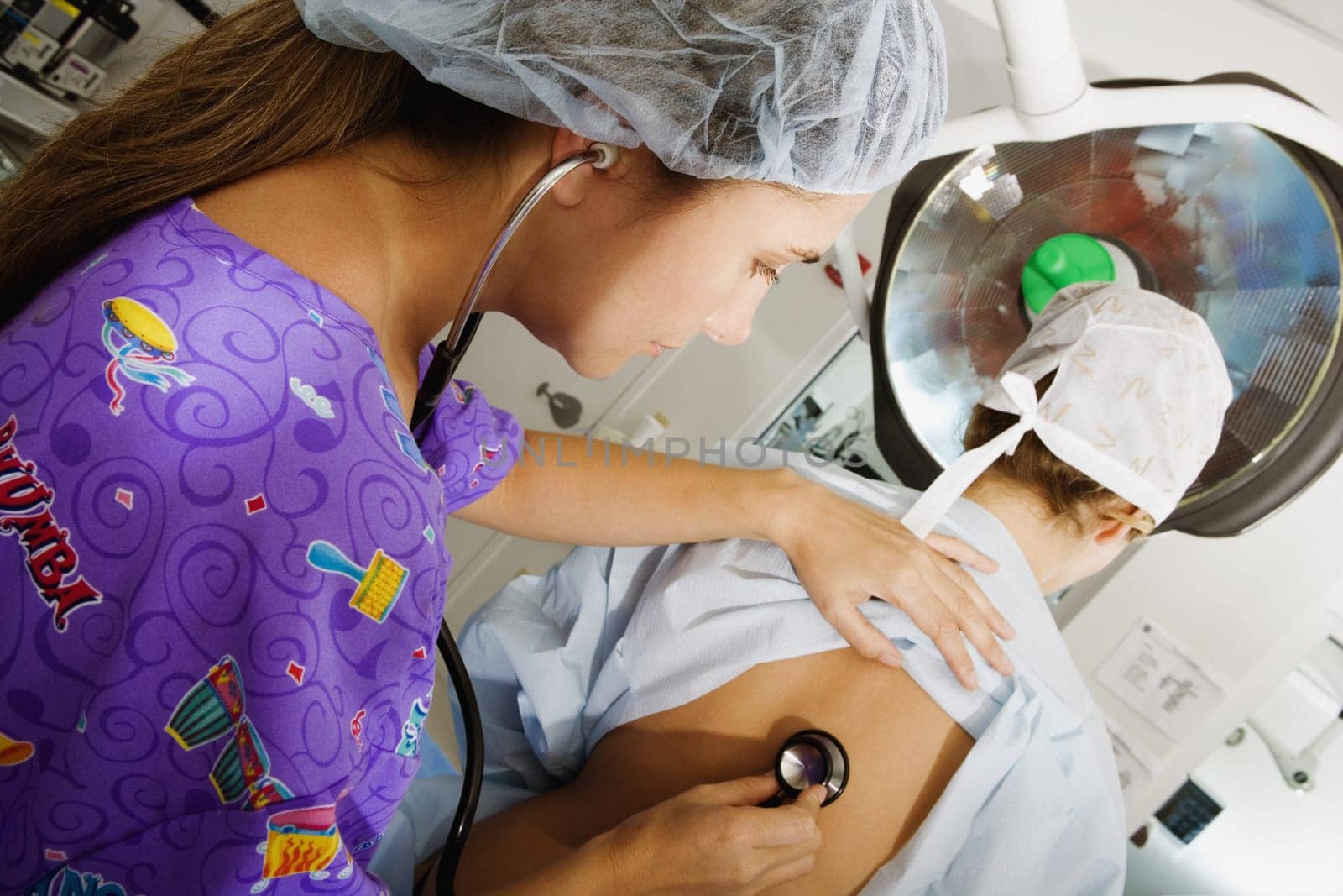 Side profile of a female doctor examining a female patient with a stethoscope