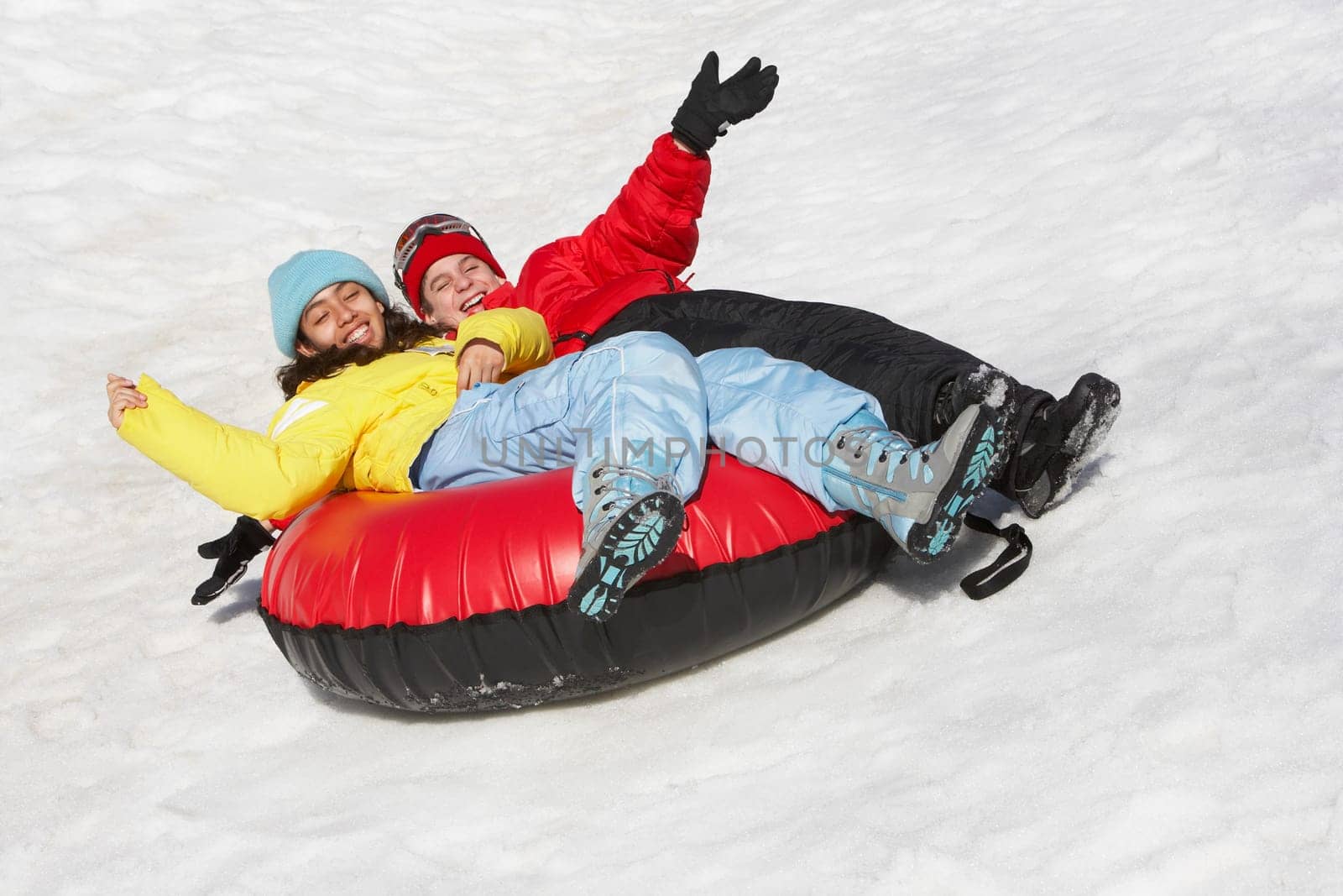 Boy and a girl sliding with an inner tube in snow