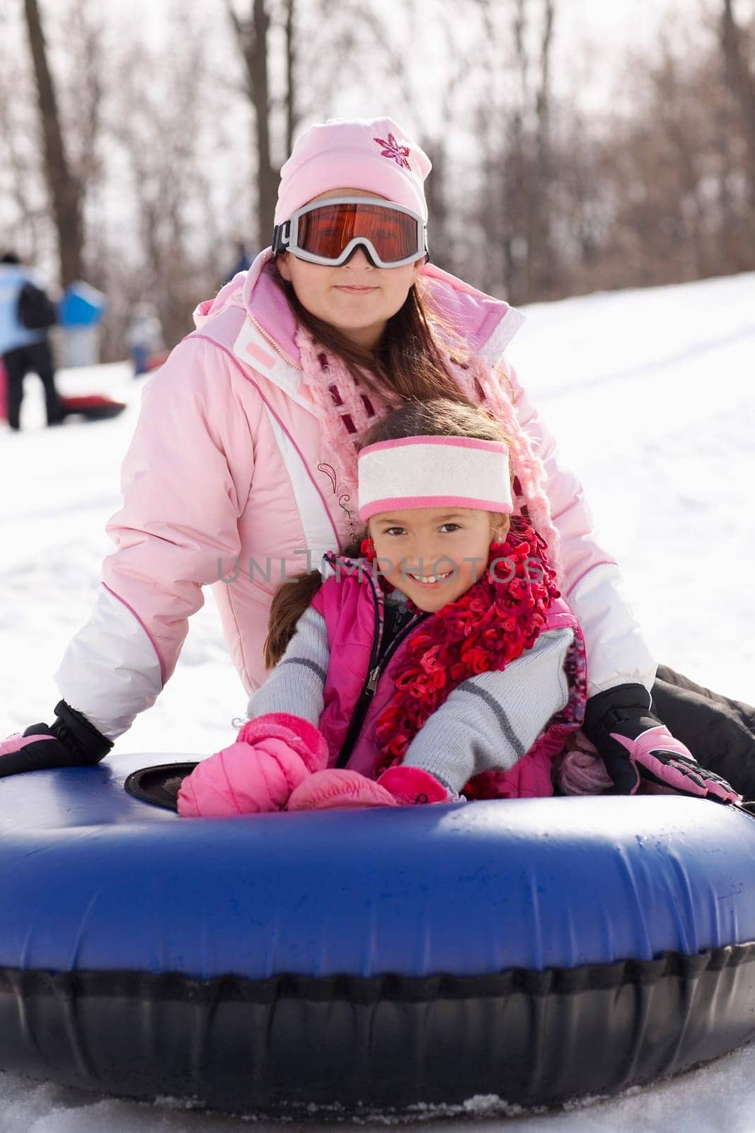 Mid adult woman sitting on an inner tube with her child in snow