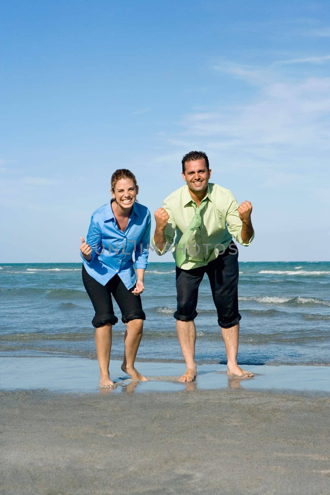 Mid adult couple clenching their fists on the beach