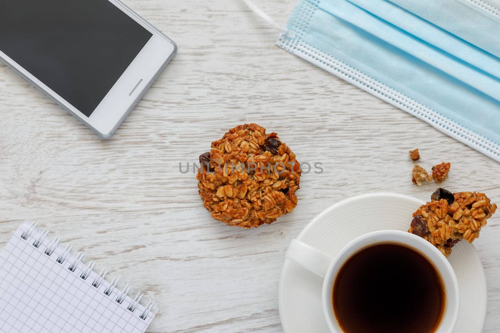 Background with coffee, cookies, notepad and medical mask, top view