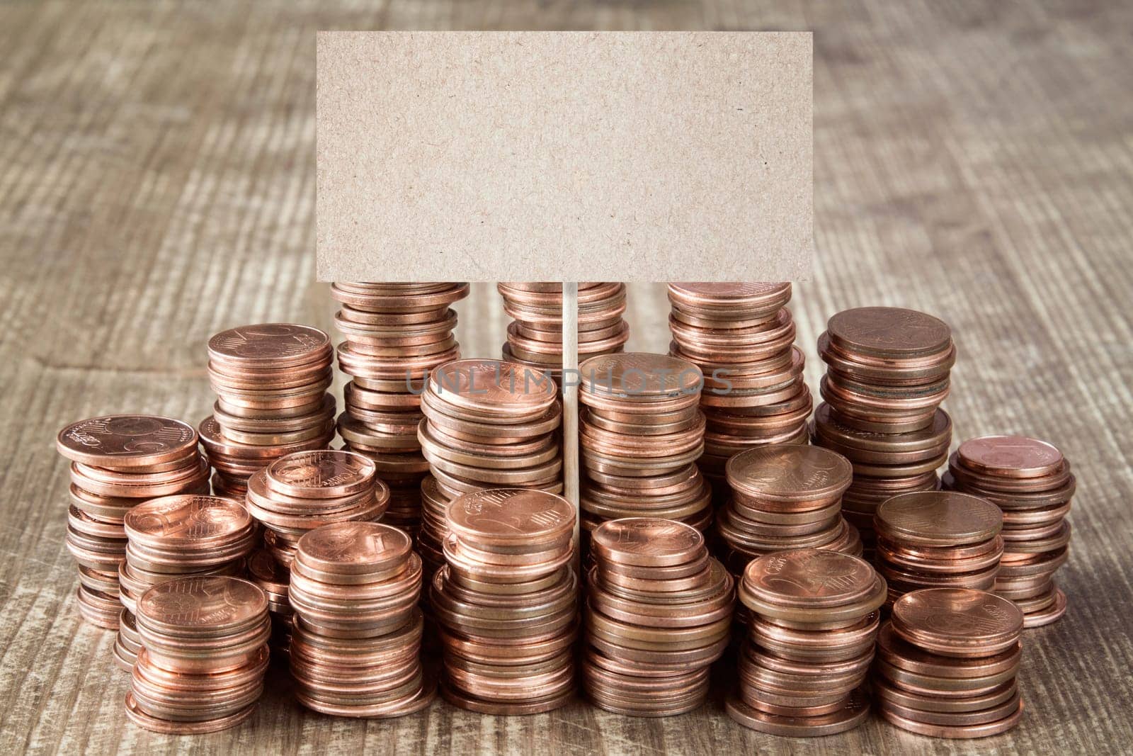 Blank sign with stacks of copper coins (Euro cents)