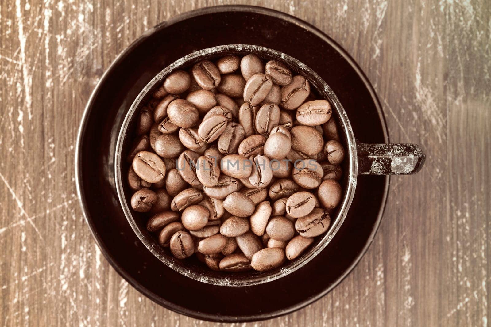 Coffee cup full of coffee beans on old wooden background.