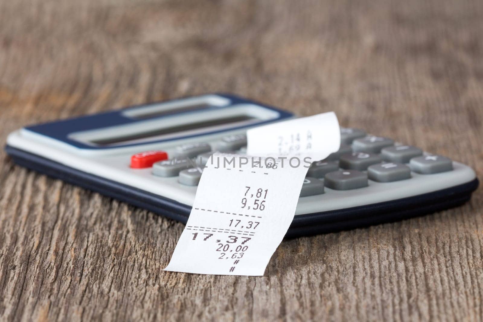 Calculator with printed receipt on wooden background