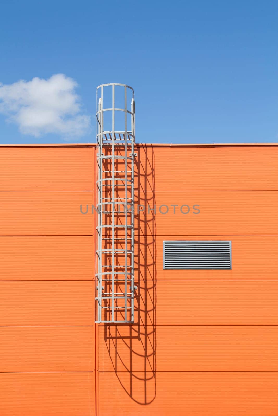 Modern industrial building wall with metal ladder,under blue sky