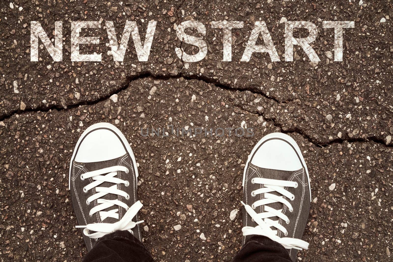 Man standing on cracked asphalt with NEW START sign