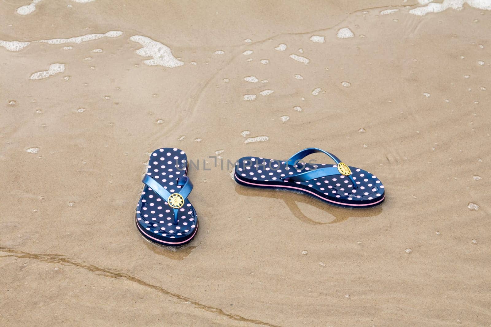 Sandal flip-flops lying on the seashore near the water