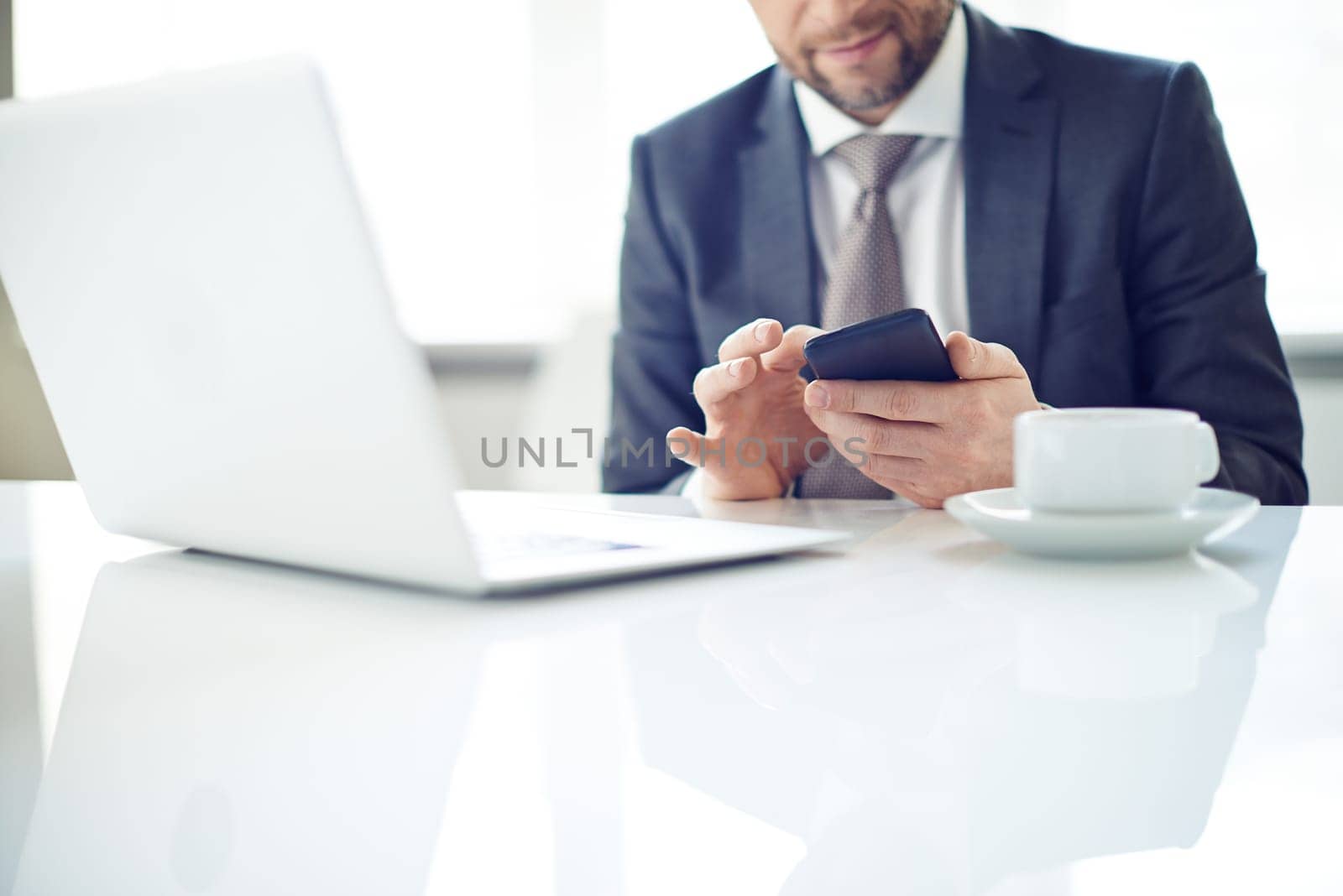 Man sitting on table and typing message on phone