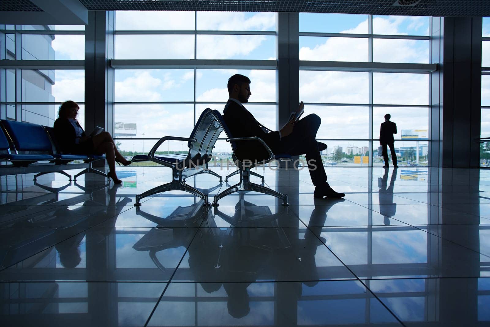 Outline of businessman reading while waiting for departure in airport