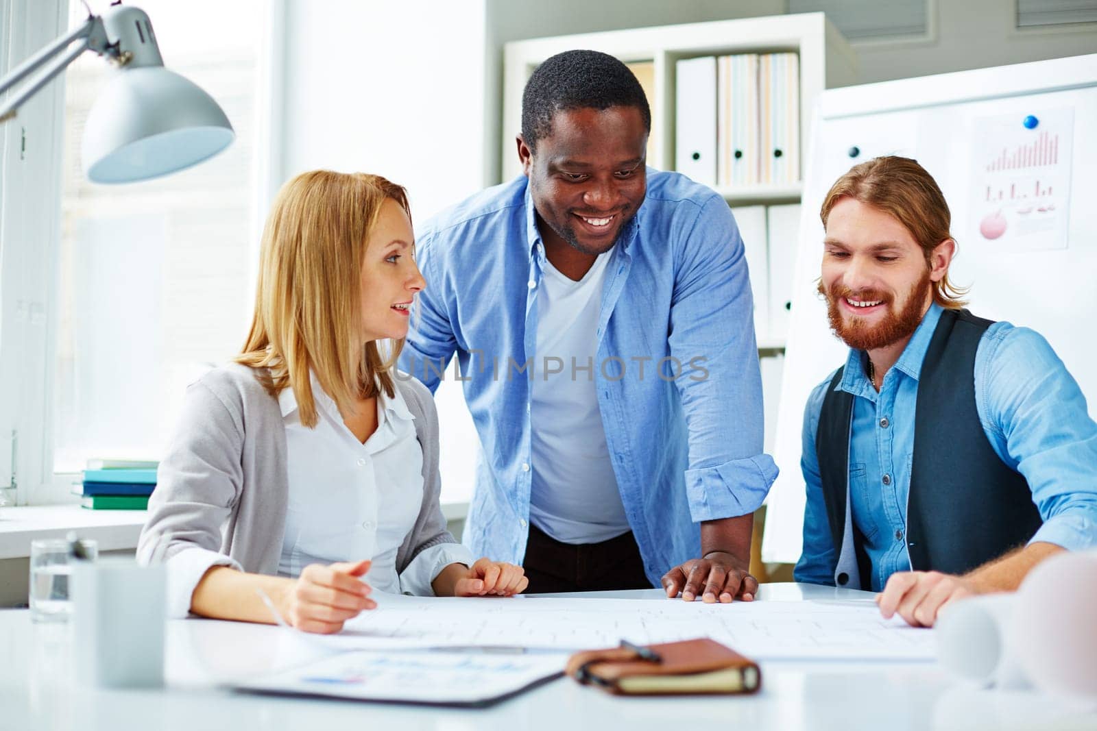 Three business people planning over blueprint