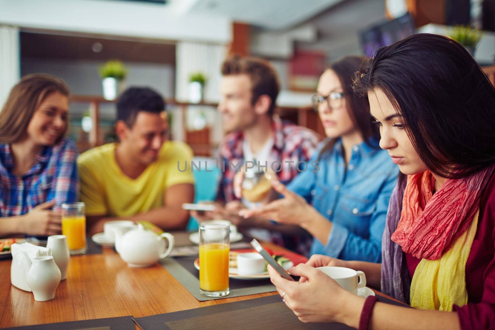 Four students eating and talking and one girl looking at telephone