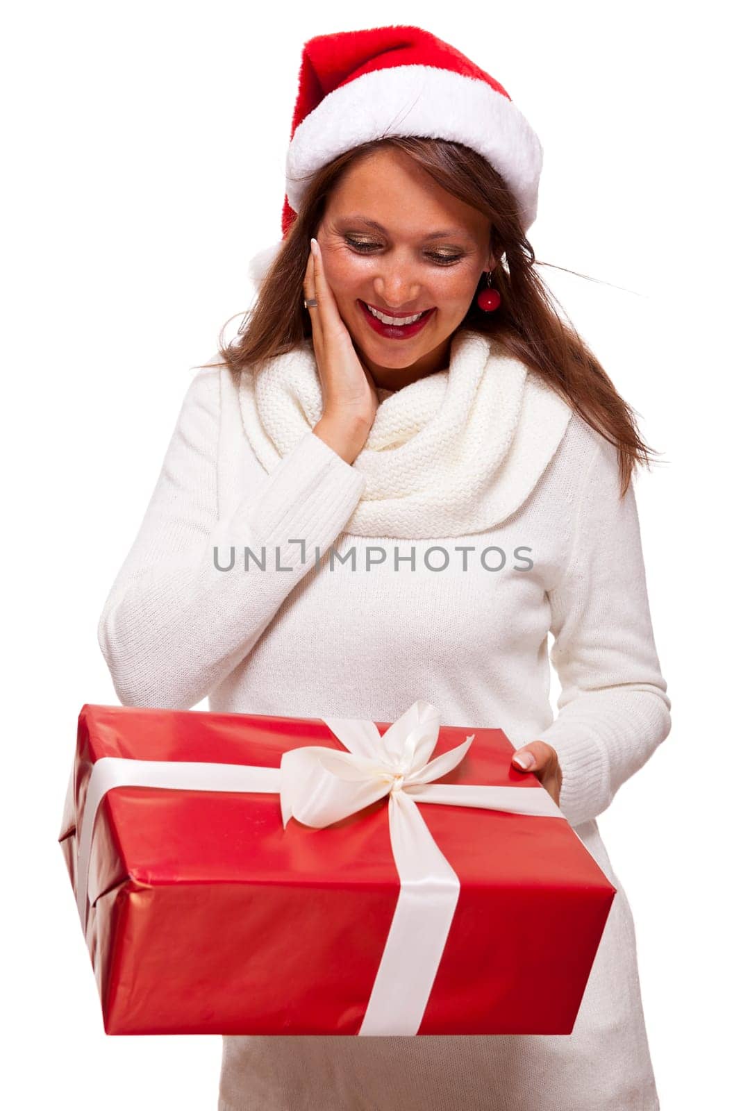 Pretty brunette woman with Christmas hat and big red gift cheerfullaughing isolated against white background