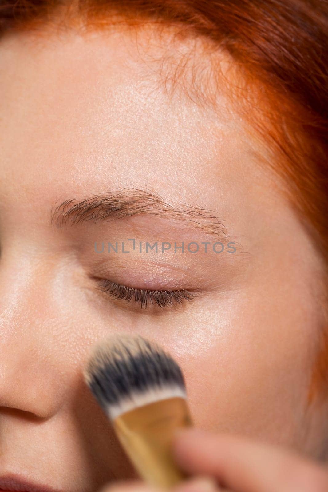 Young pretty woman with red hair wears makeup on nak shot portrait isolated against white background