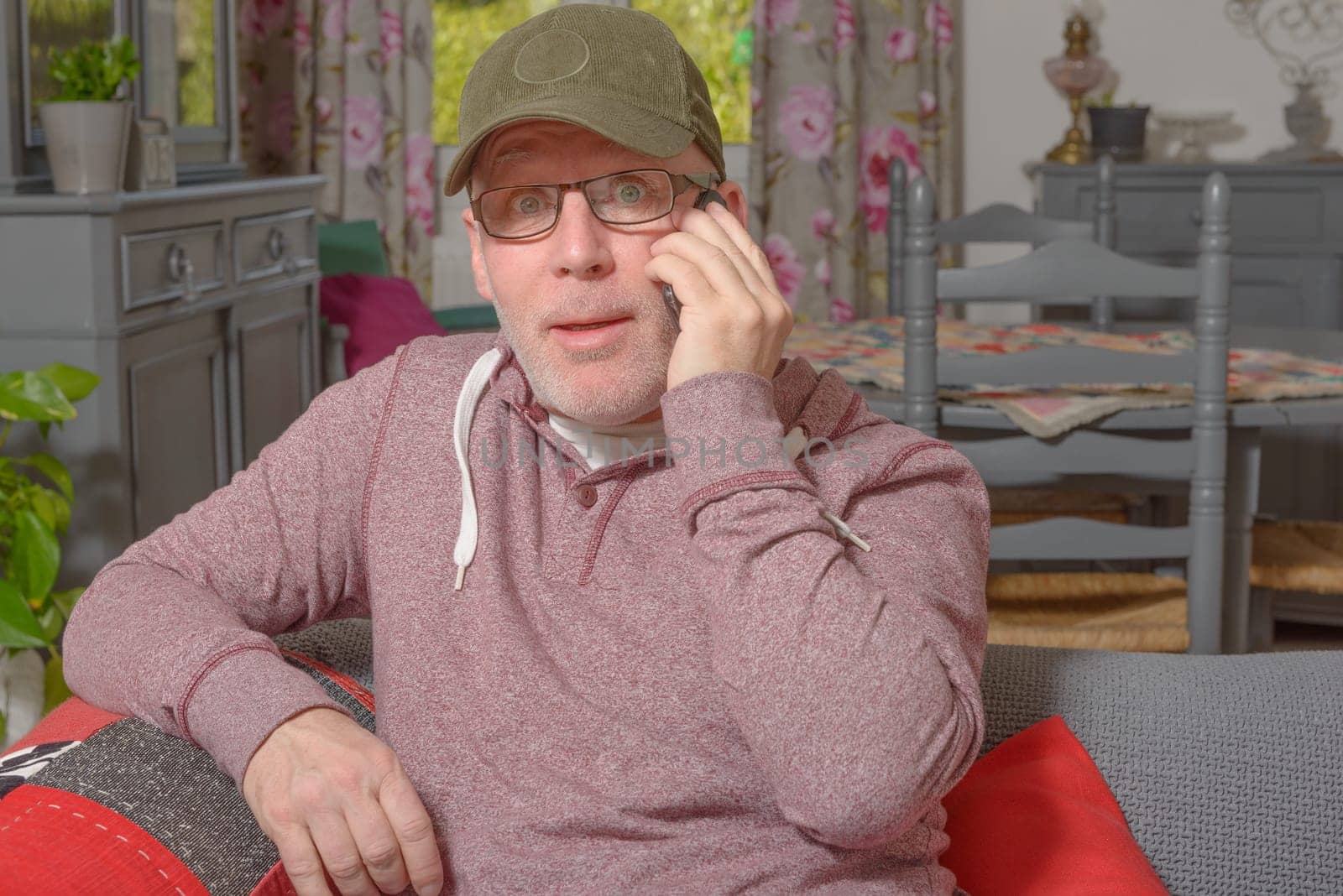 a senior with a phone sitting on the sofa in his house