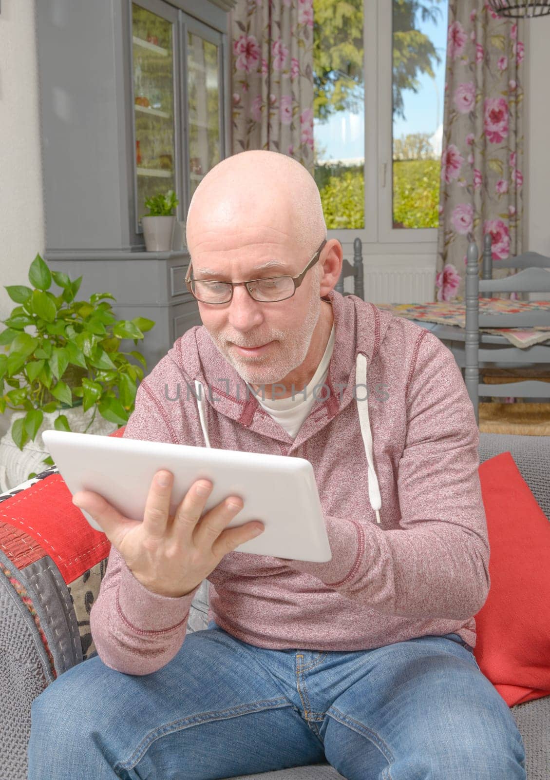 a senior man with a digital tablet on the sofa
