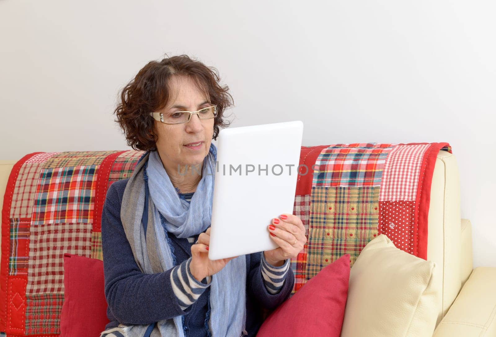a middle aged woman with a digital tablet on the sofa