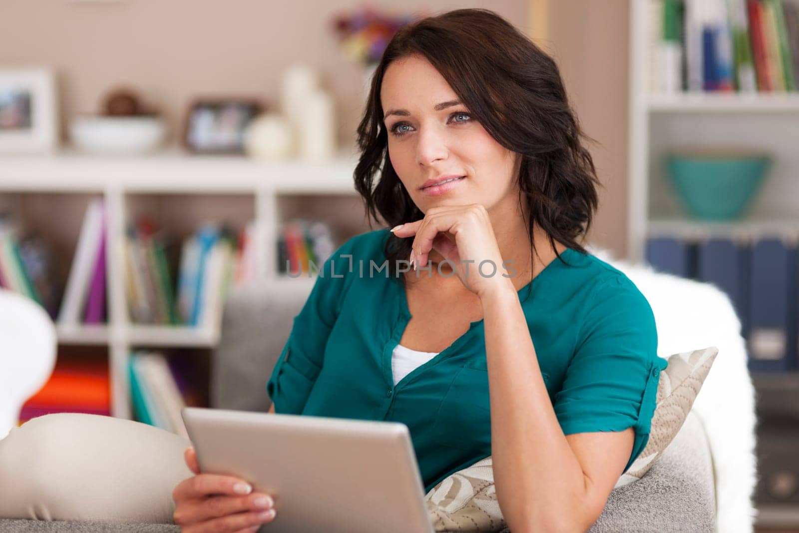Pensive brunette woman using digital tablet at home