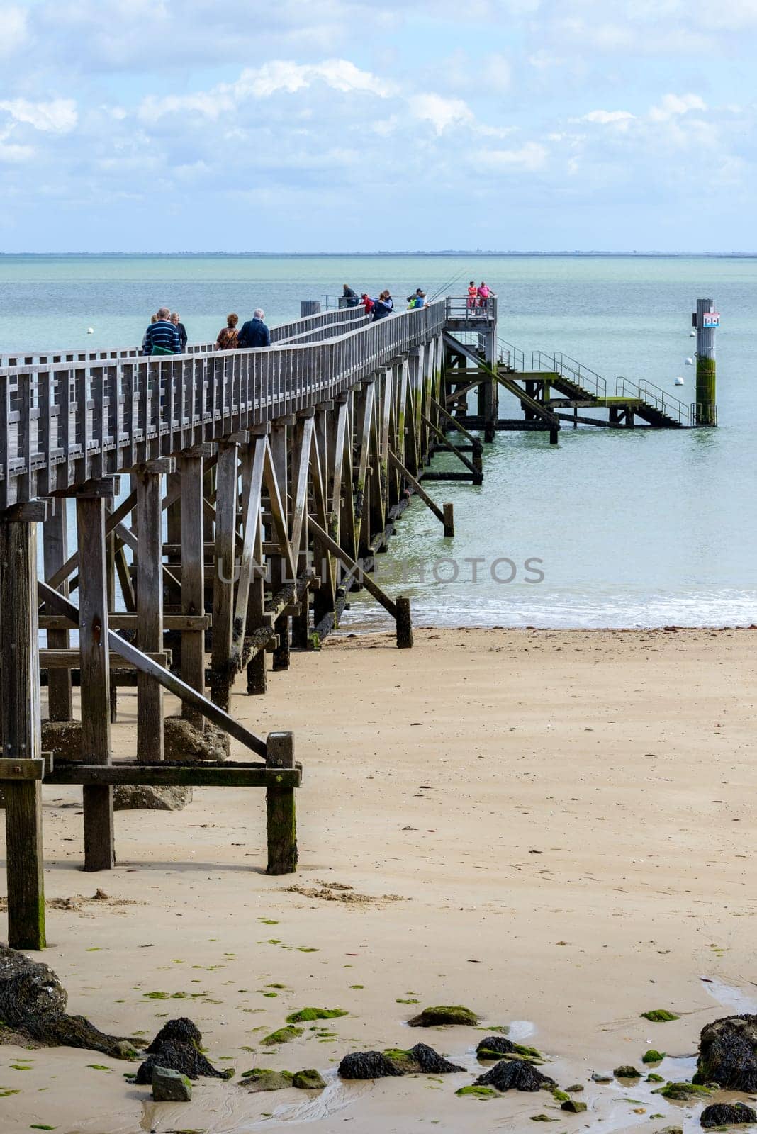 NOIRMOUTIER, FRANCE - CIRCA SEPTEMBER 2015: People walk and fish on the pier on Plage des Dames.