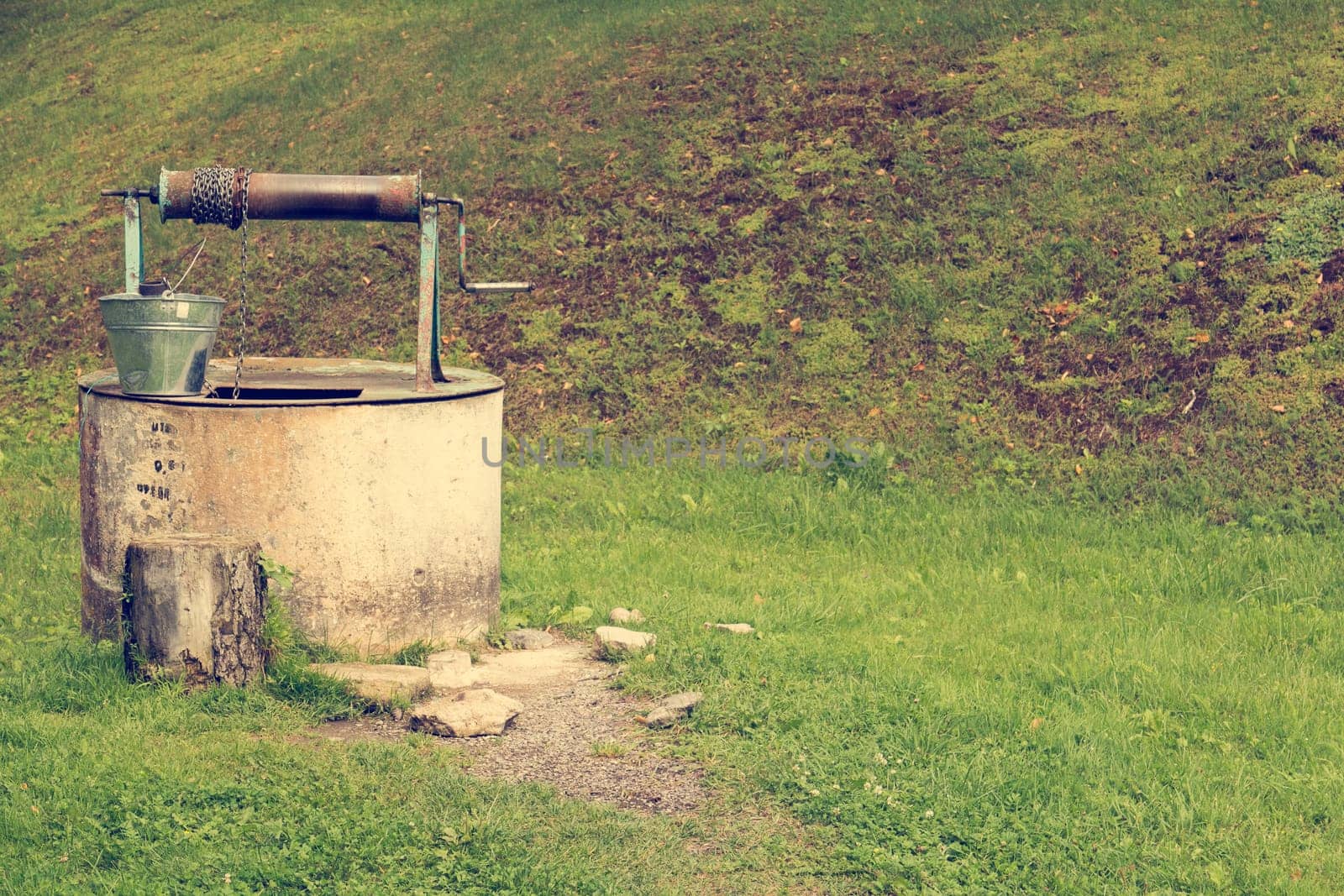 Old well with metal bucket in the village