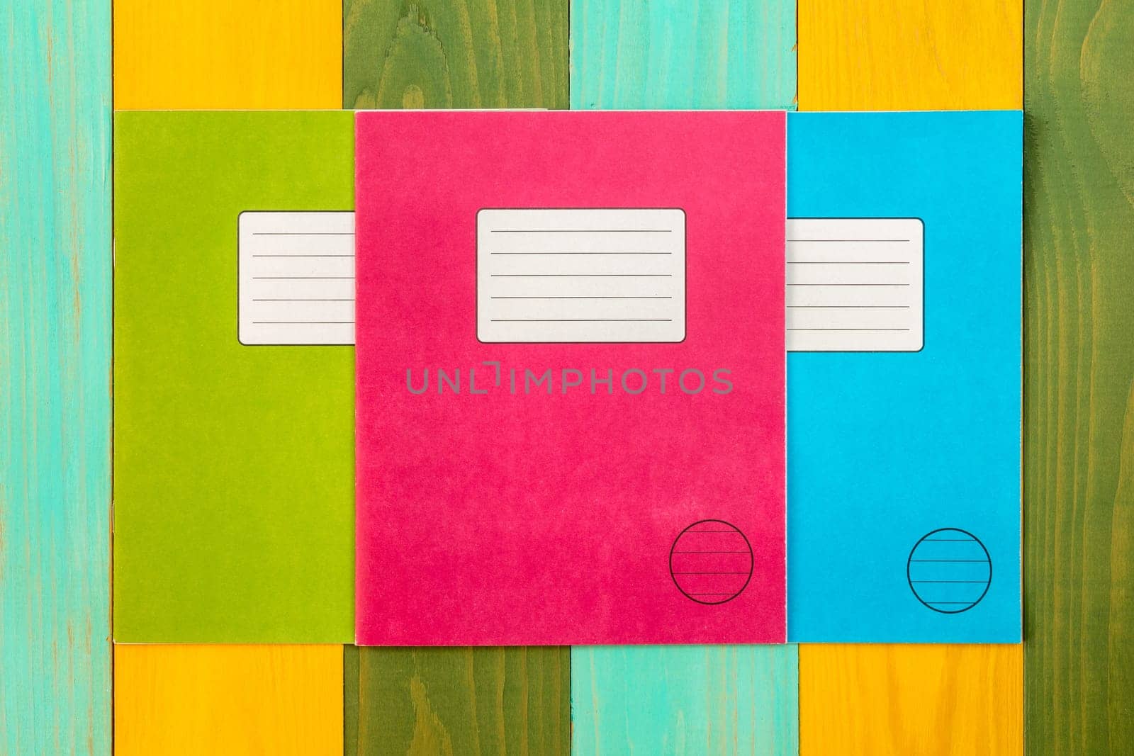 Three  exercise books on the colorful wooden background