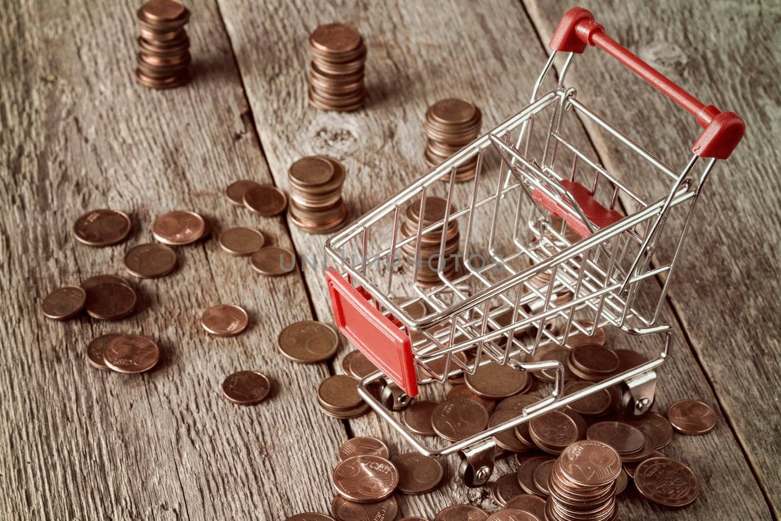Shopping cart with coins on wooden background. Retail,sale or marketing concept
