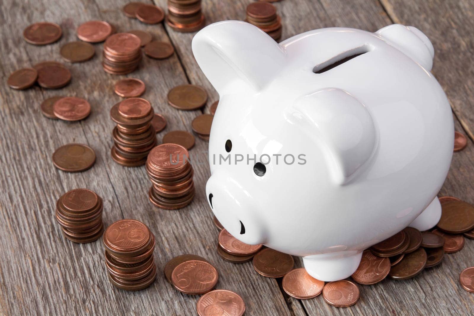 White piggy bank standing among pile of coins