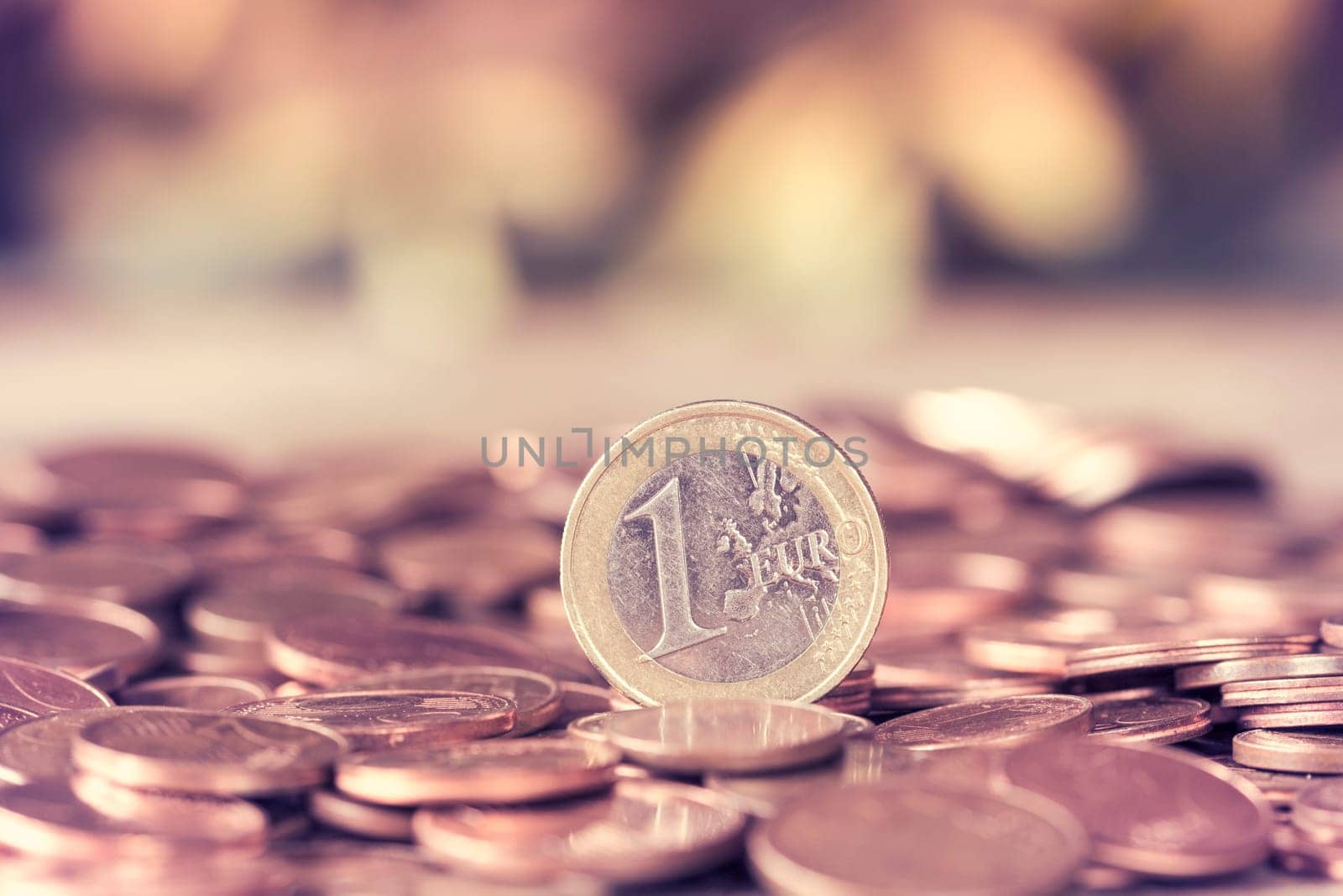 Euro coins. One Euro coin on the cents pile. Shallow depth of field