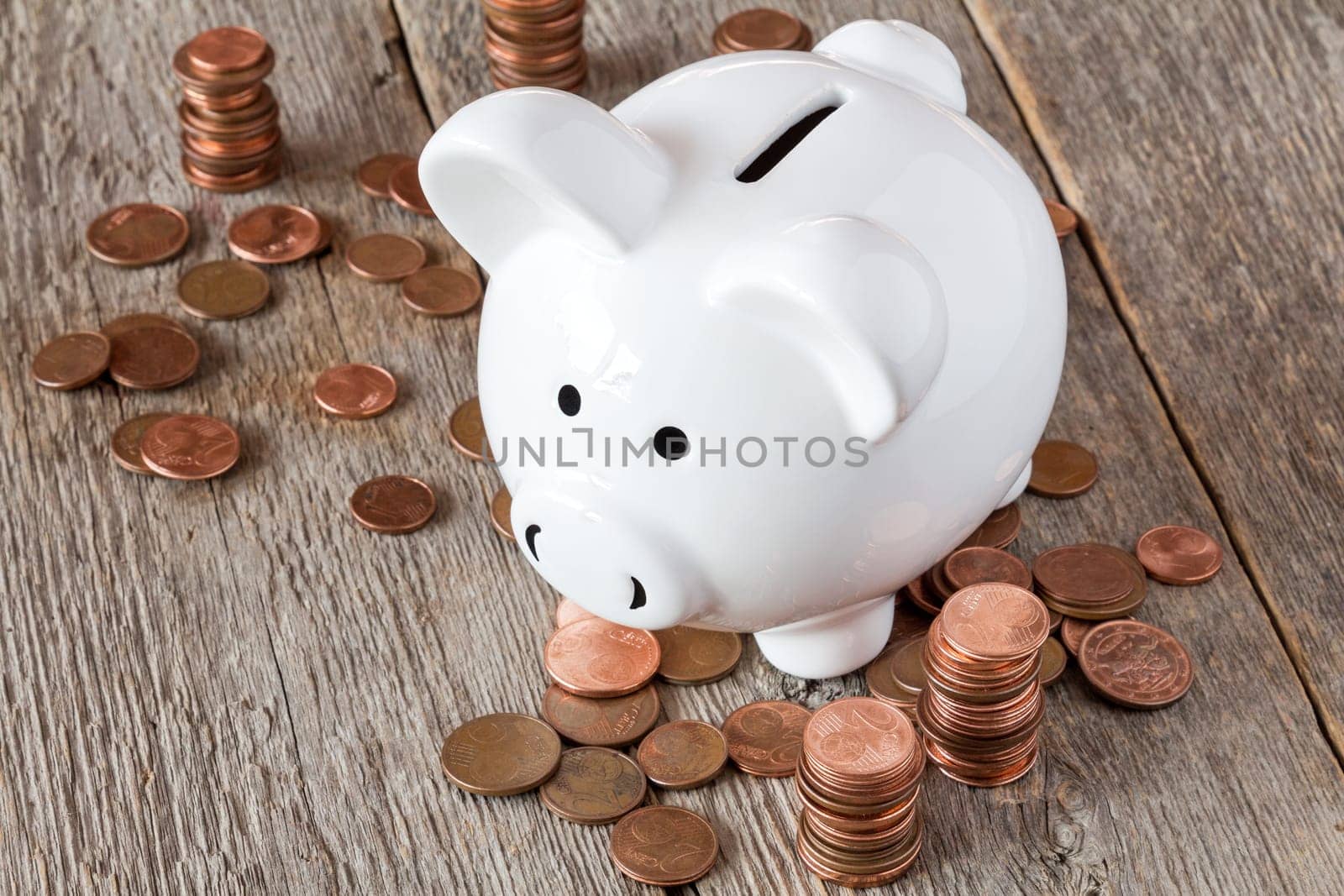 Piggy bank standing among pile of coins