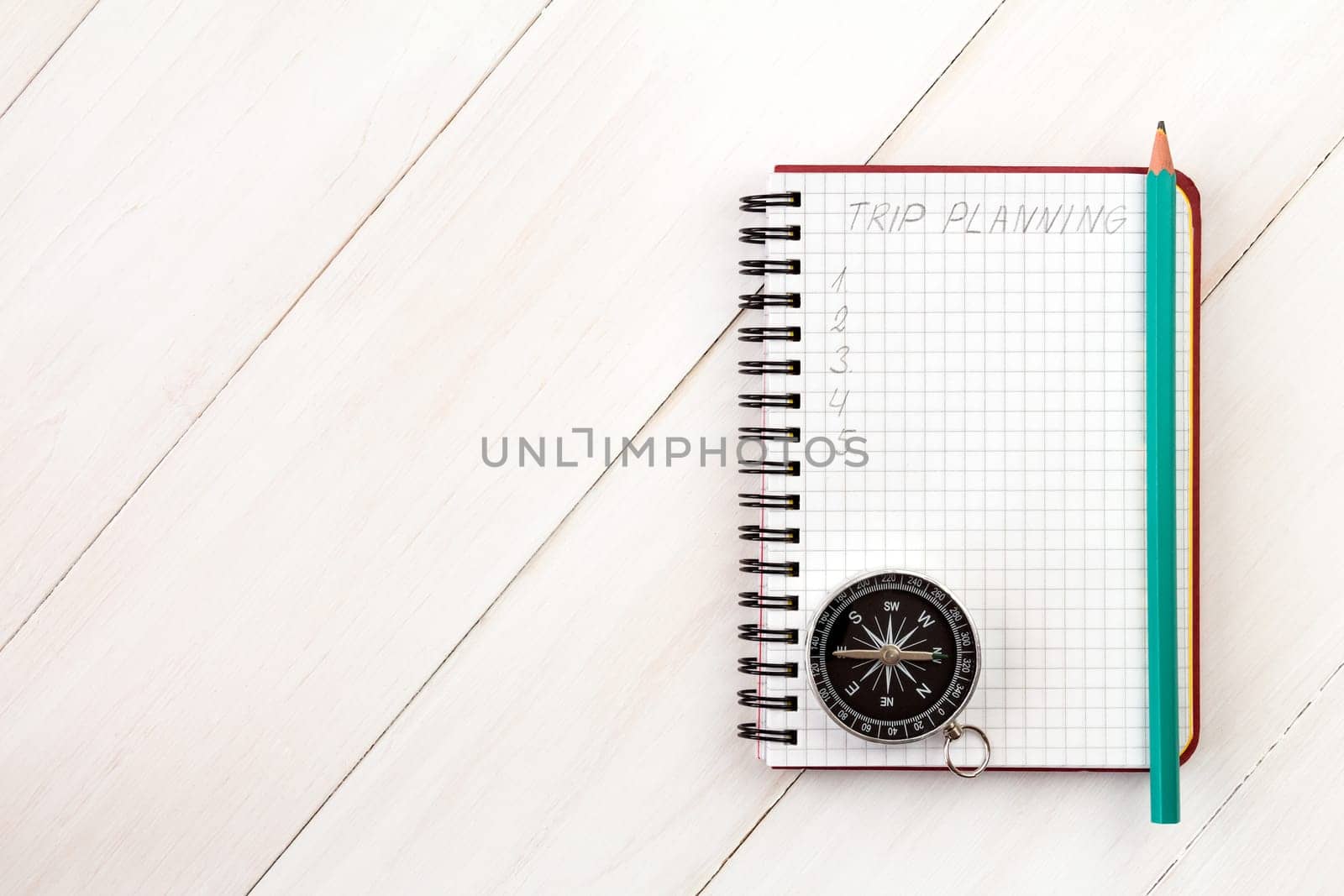 Traveler's notebook with compass and pencil on wooden background