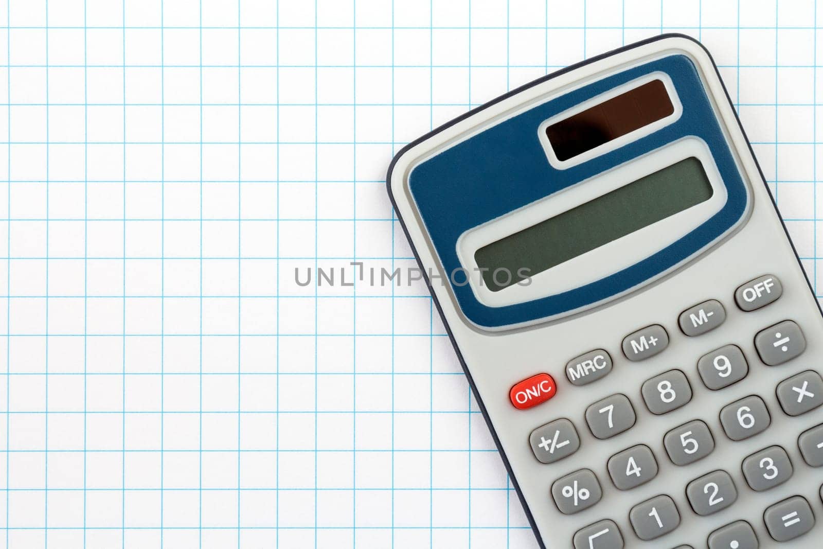 Electronic digital calculator on squared paper background