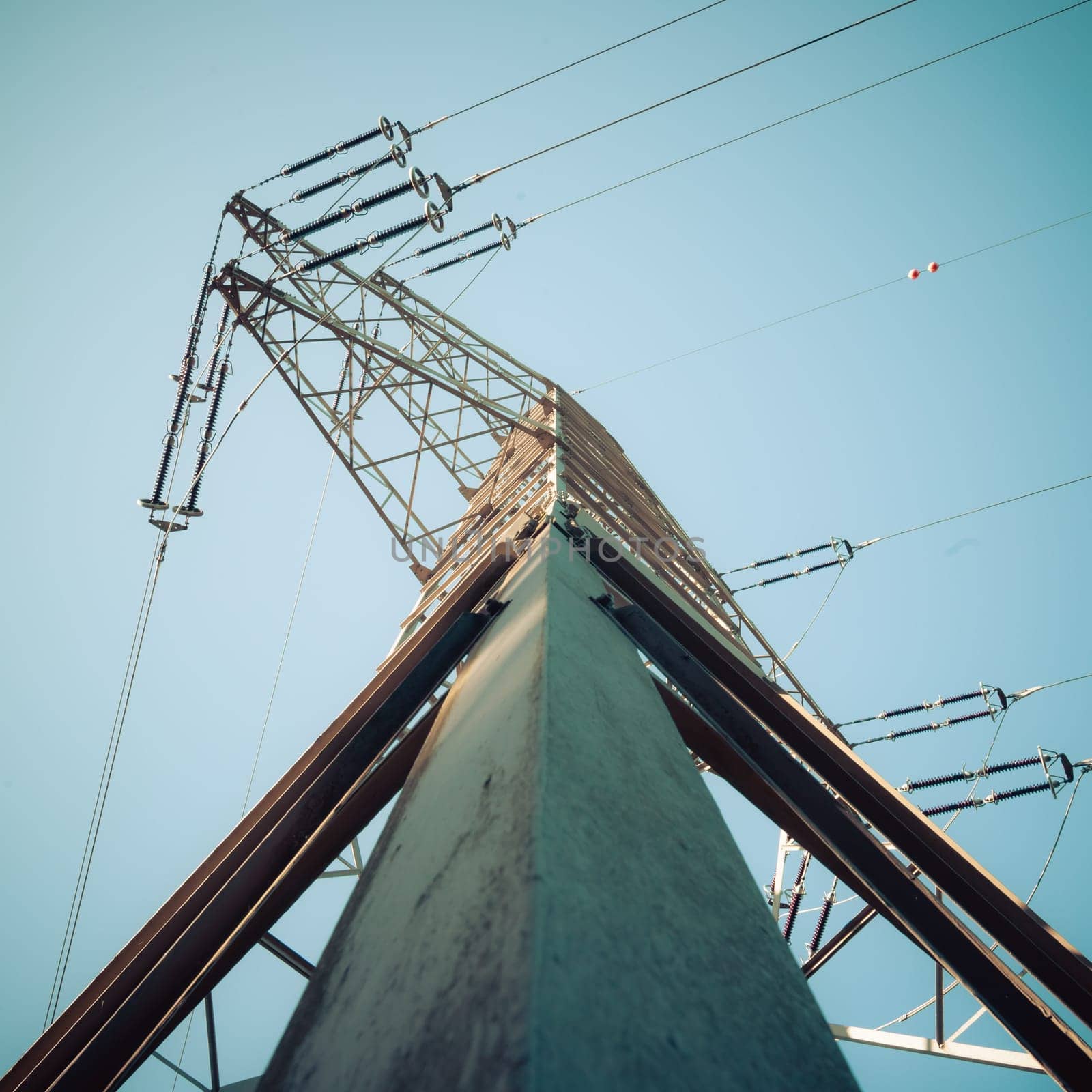 Picture of an electrical tower or pylon, blue sky in the background. Power grid or smart grid.