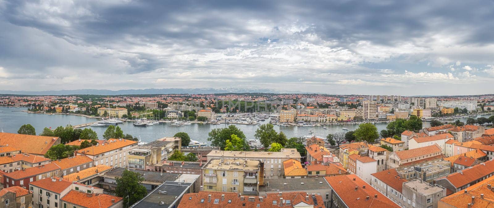 Large panorama with drone or birds eye view on orange tiled roofs and cityscape of Zadar. Bay or marina with moored yachts and boats, Croatia