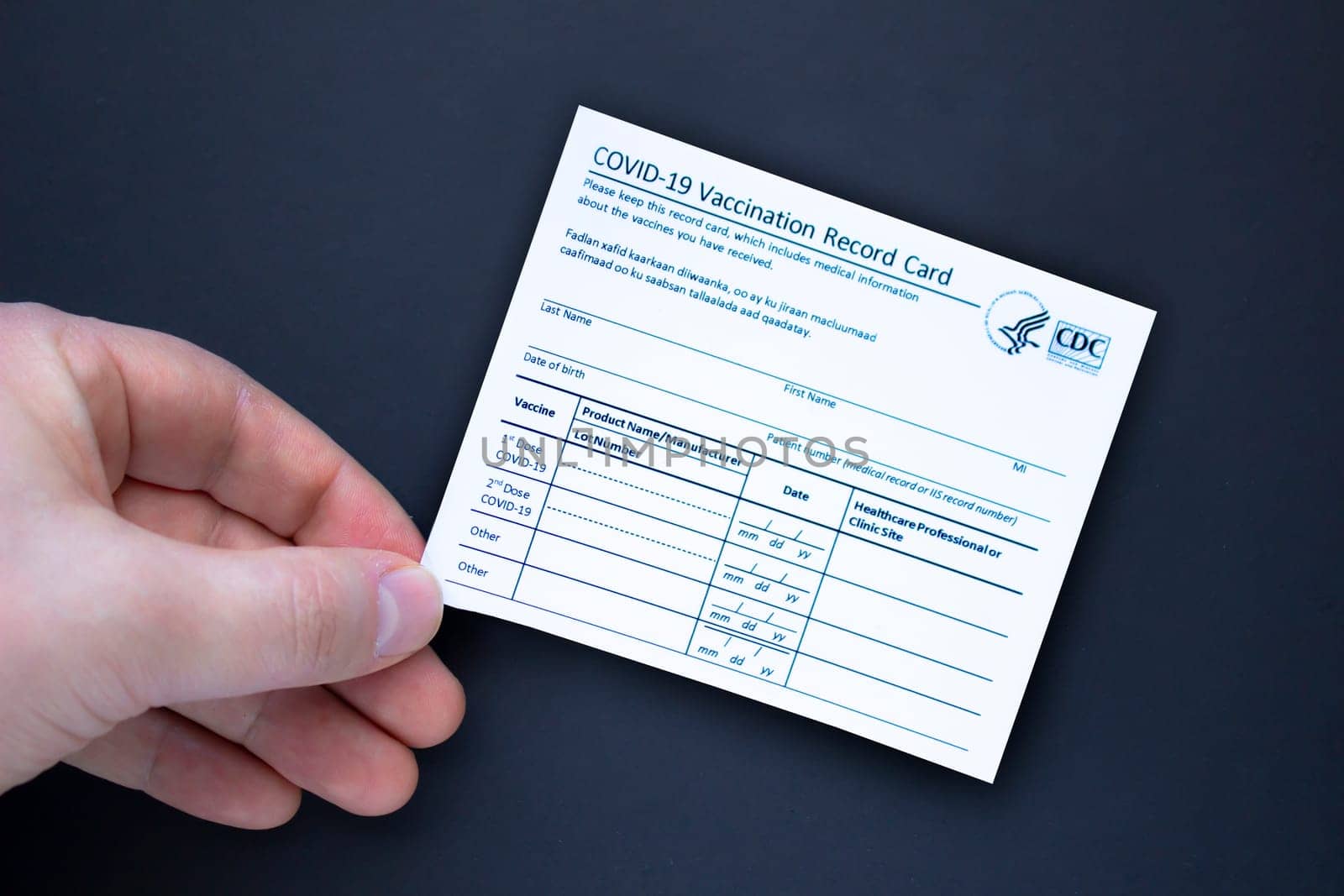 Calgary, Alberta. Canada. Feb 3, 2021. A person holding a COVID-19 Vaccination record card on a black background.
