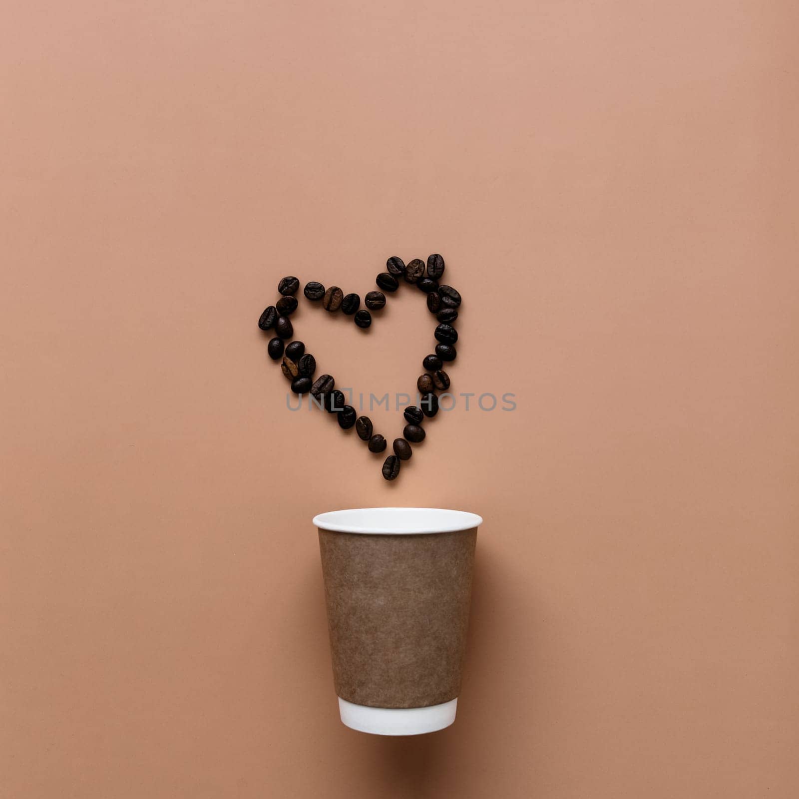 Beige background with paper coffee cup, coffee beans heart shape. High quality photo