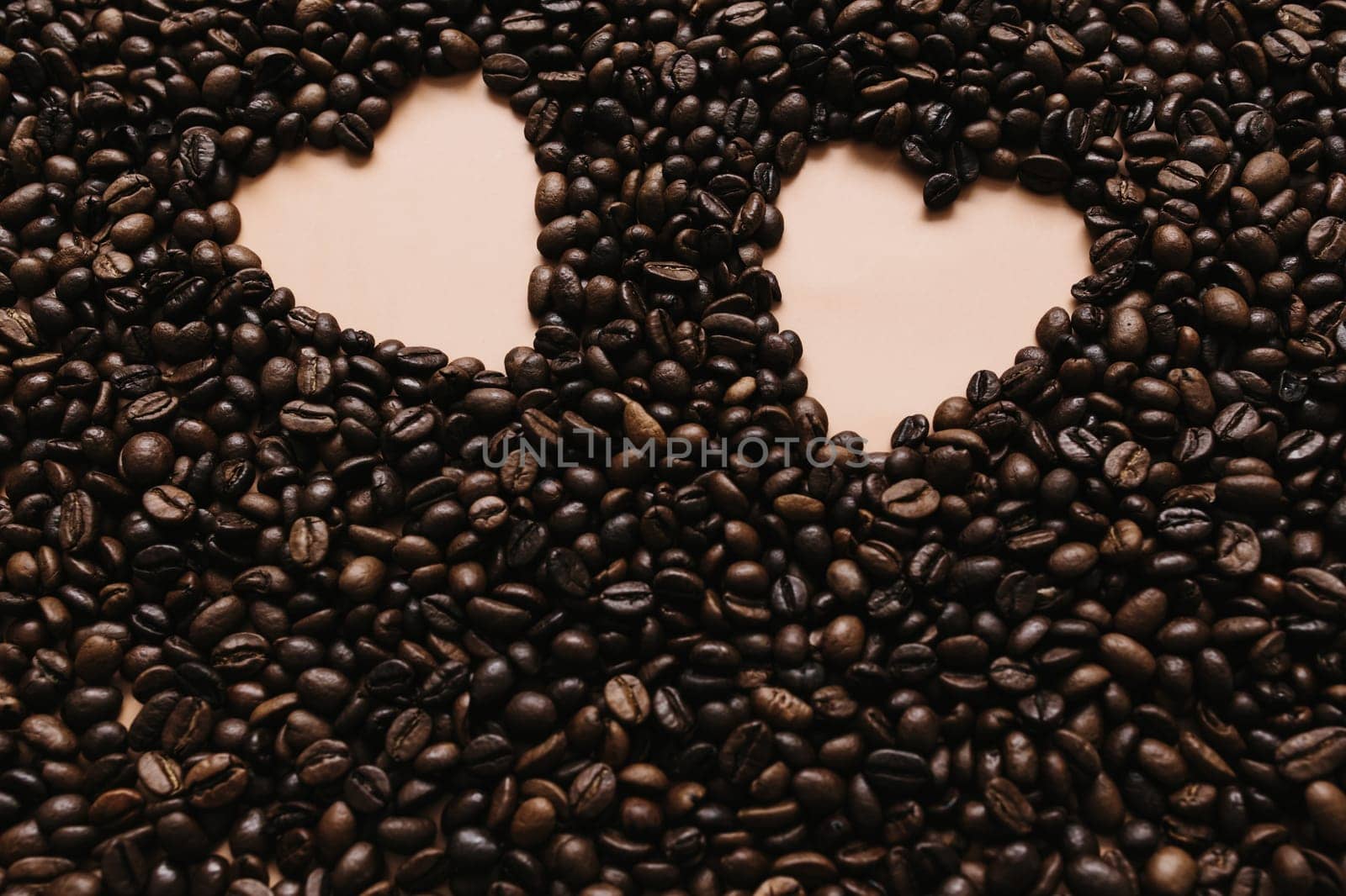 Background with array of dry coffee beans with two heart shapes. Beige. High quality photo