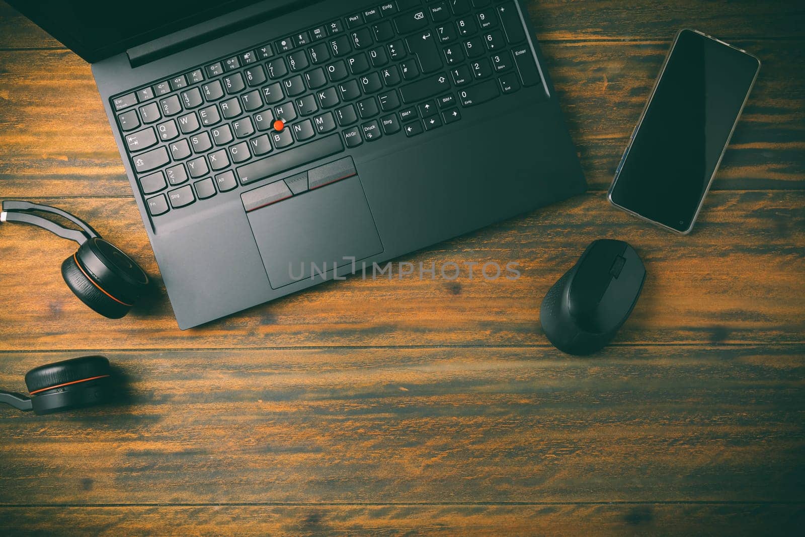 Working place and office desk with laptop, headset, smartphone and computer mouse, wooden background