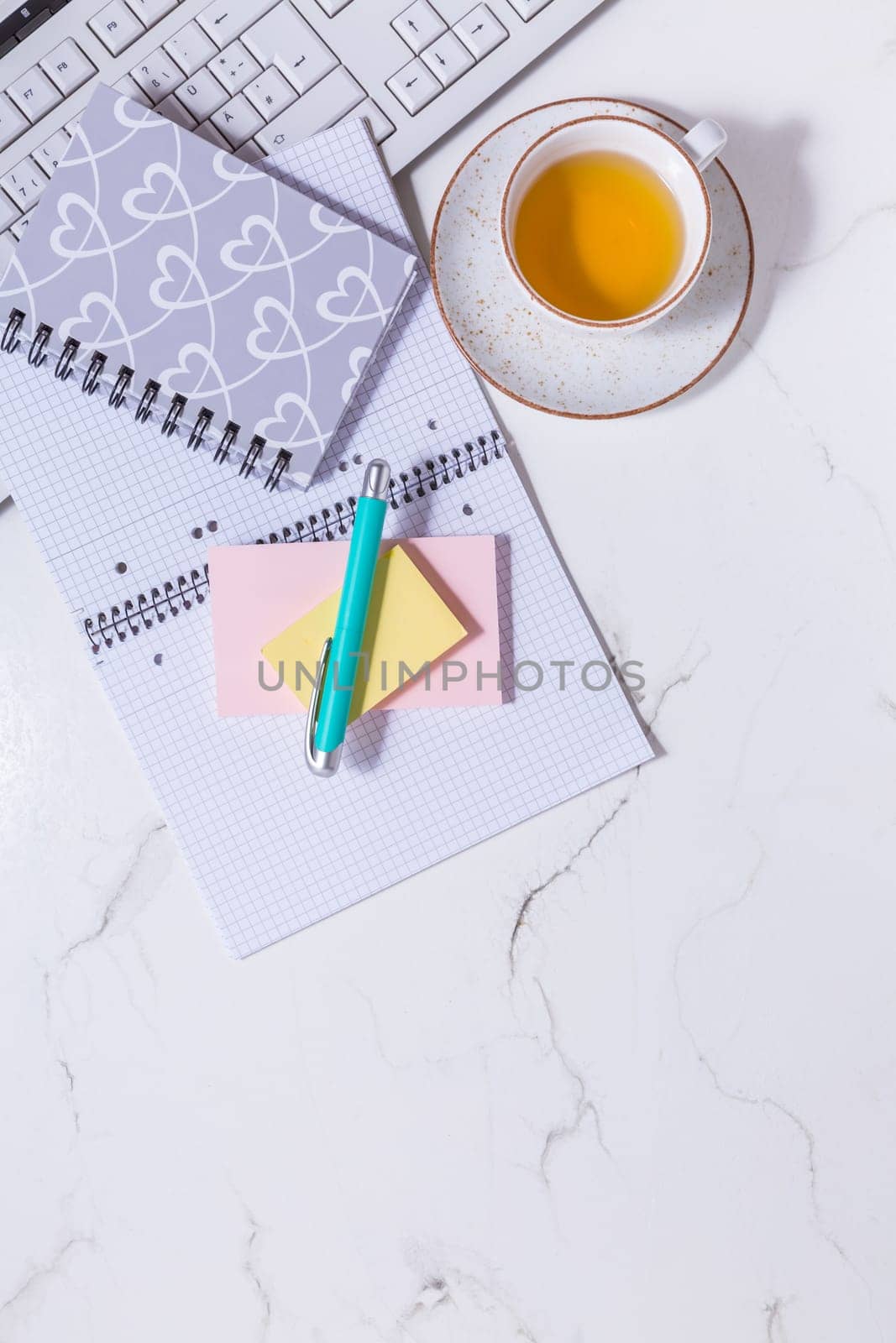 Flat lay home business desk - cup of tea, with communication device with and writing tools. Feminine business mockup, copyspace, white background.