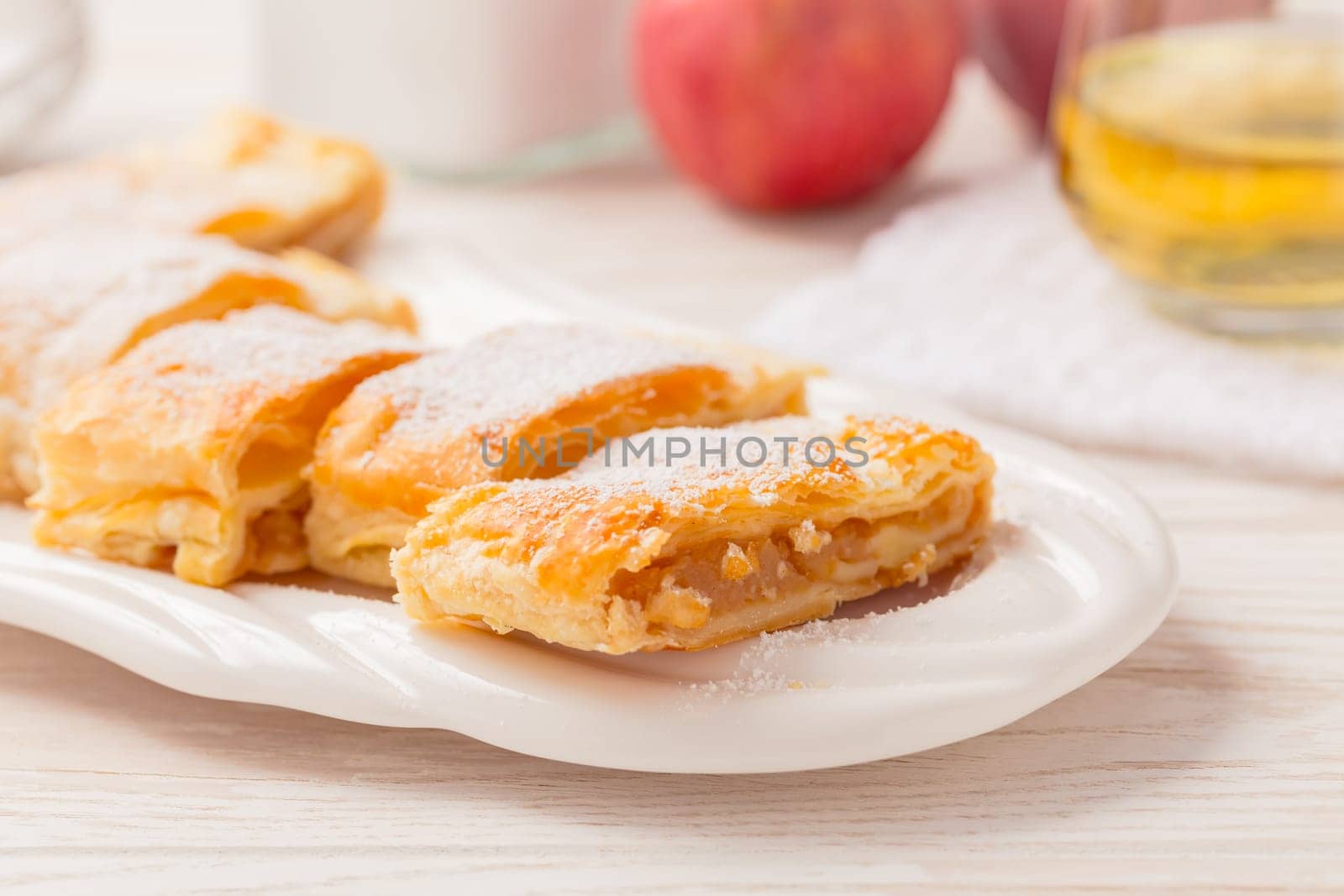 Homemade apple strudel (apfelstrudel) on white plate. Popular pastry cake in Europe
