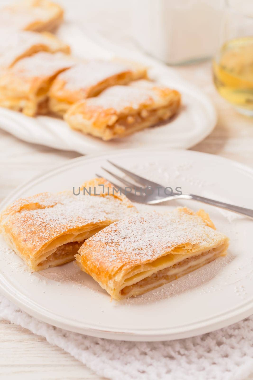 Homemade apple strudel (apfelstrudel) on white plate. Popular pastry cake in Europe