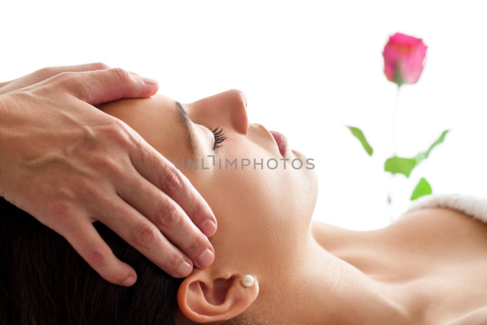 Close up portrait of Woman having Facial massage. Therapist massaging woman’s head isolated against white background.
