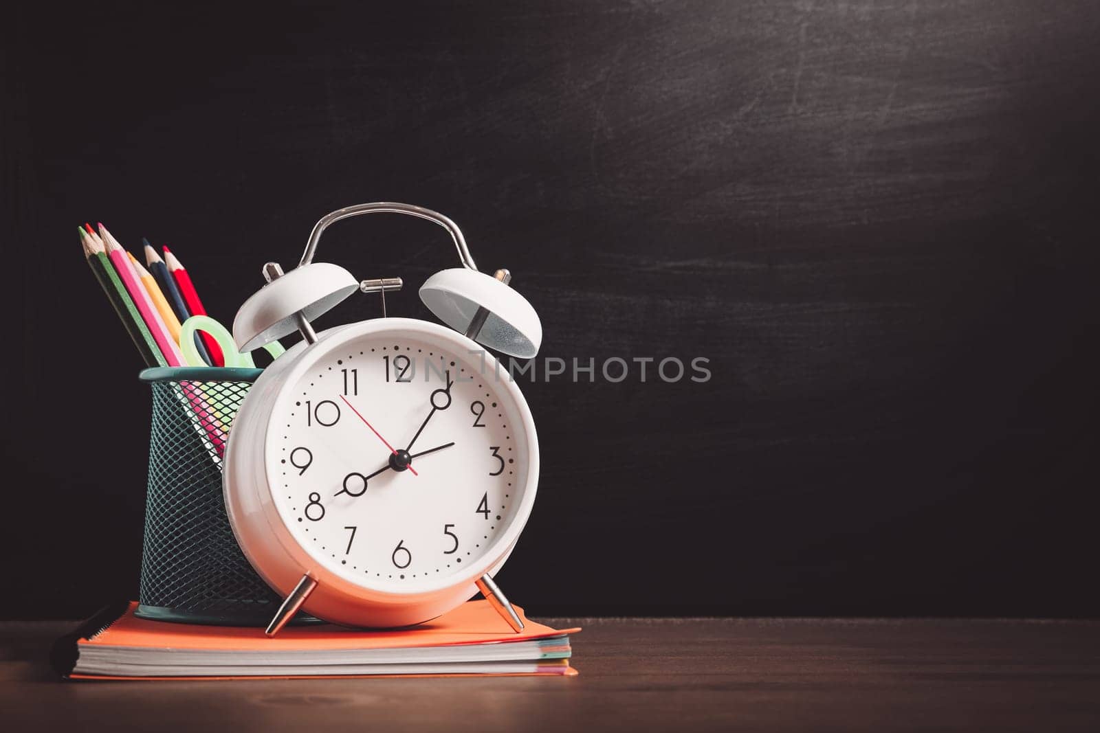 school accessories on the table with blackboard background. Pencils and books