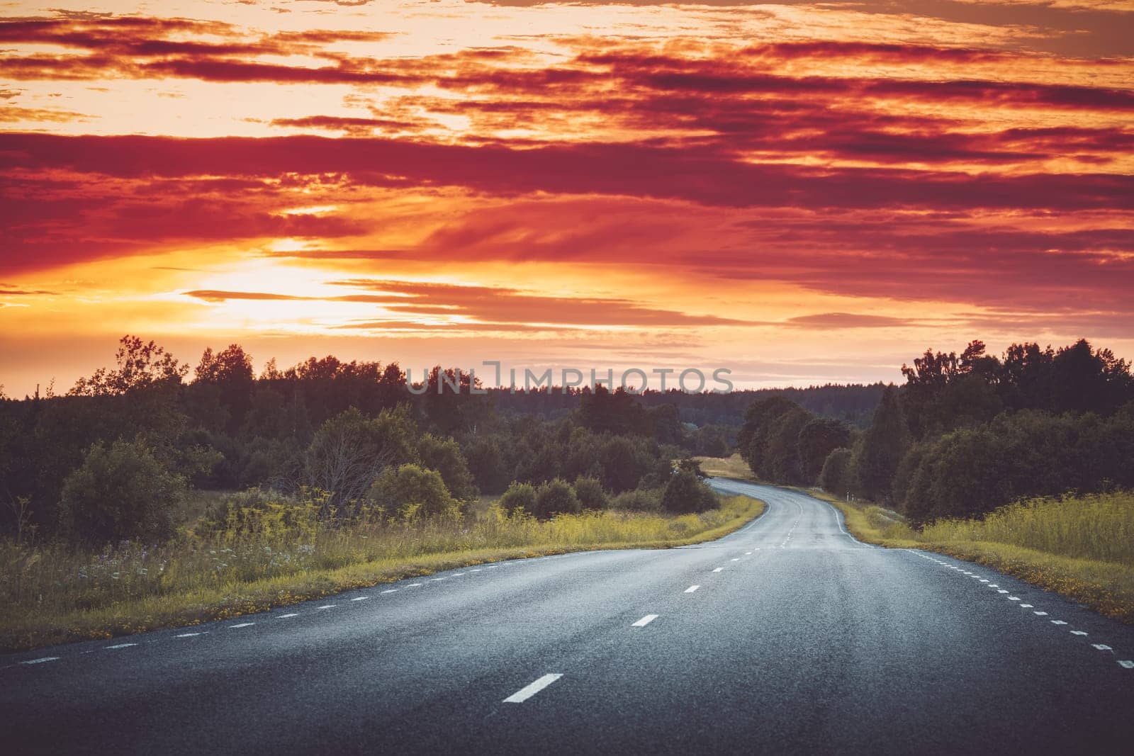 Beautiful road panorama on sunny spring evening. Asphalt way view in countryside at the sunset