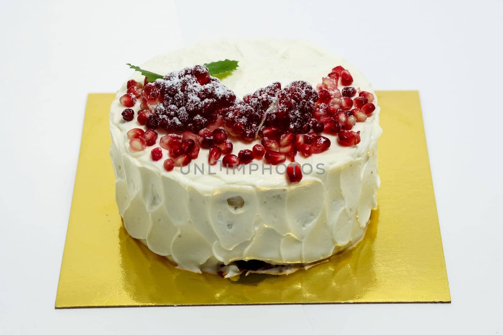 Cake sprinkled with pomegranate berries. Cake on a white background.