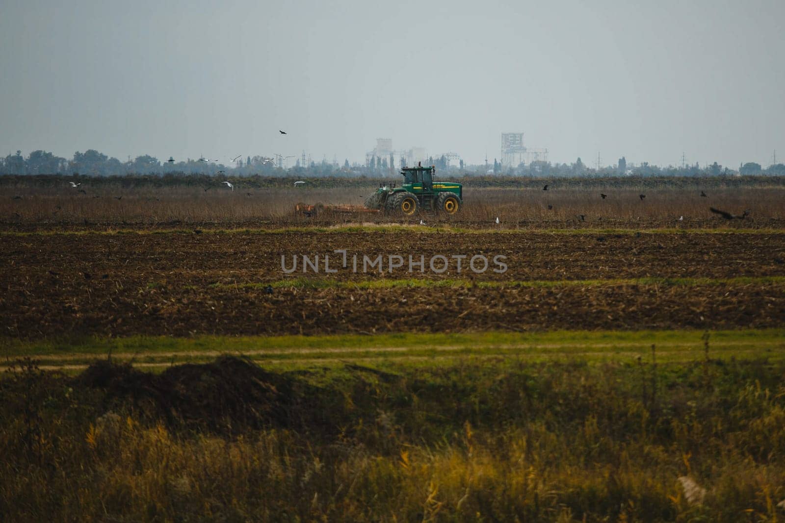 The tractor plows the field with a plough. Ploughing the soil.